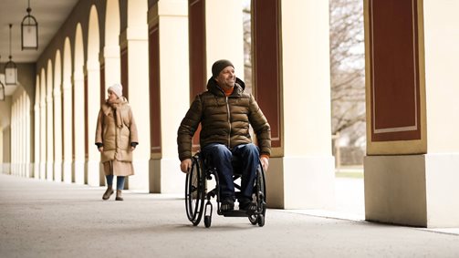 Osoba jadąca składanym wózkiem inwalidzkim